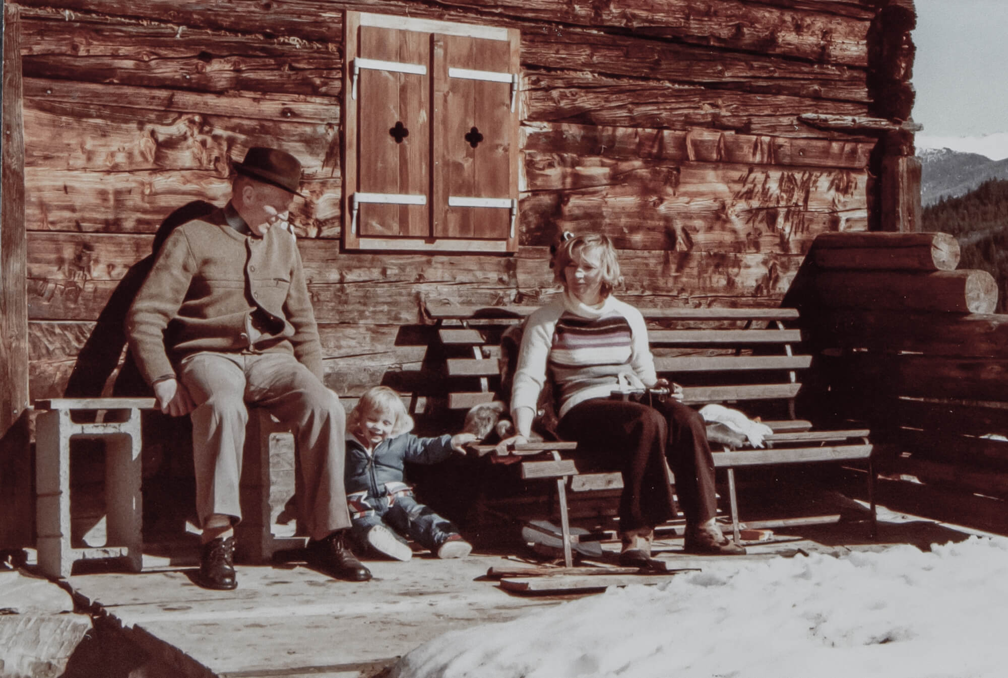 Die Familie sitzt vor der Almhütte (altes Foto).