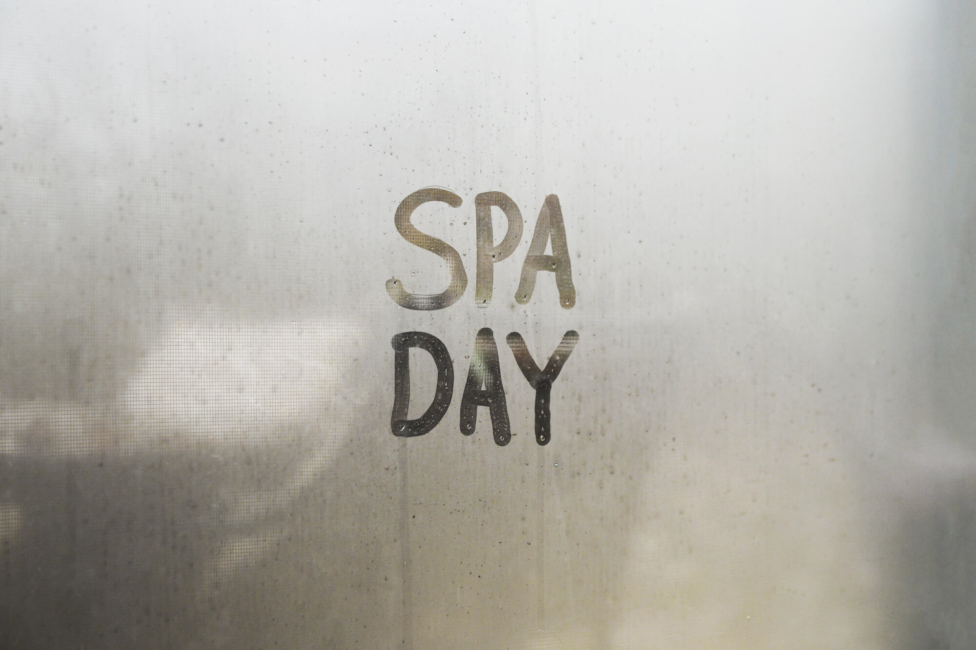 Dampf an Glasscheibe mit Text Spa Day.