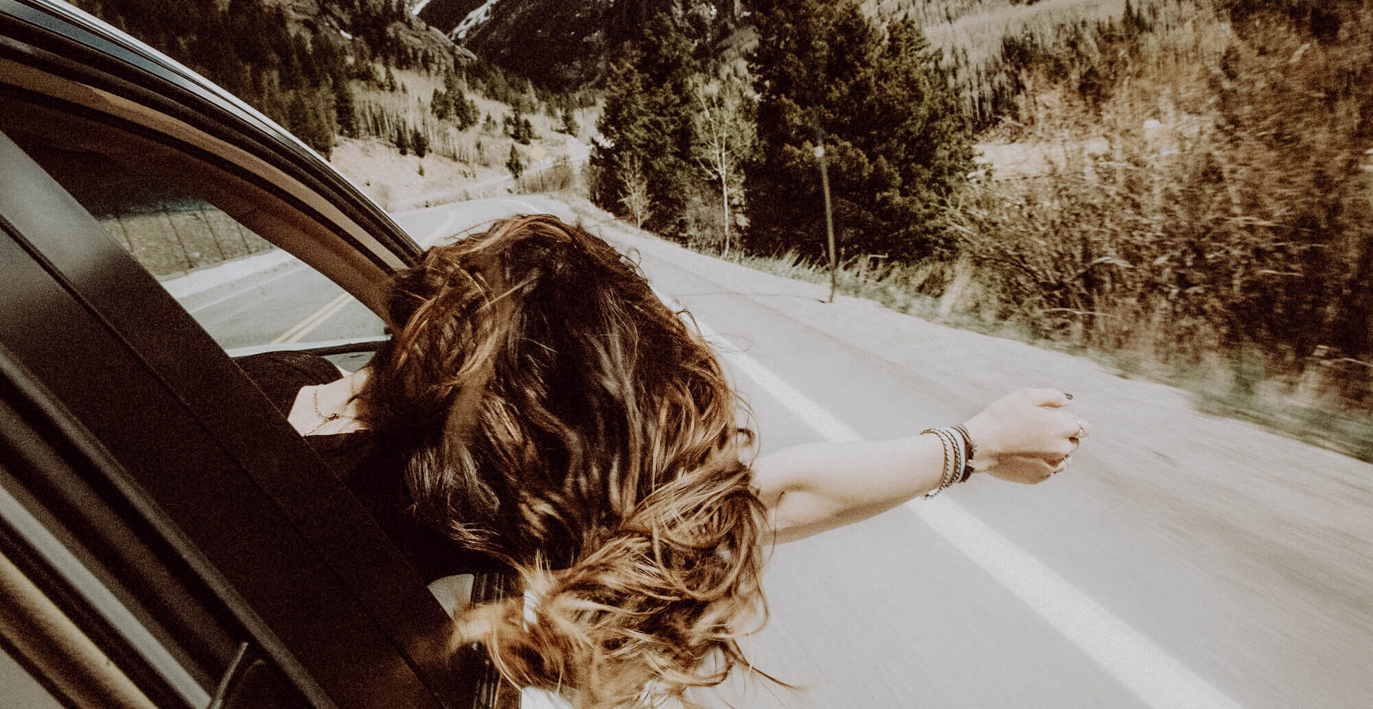 Eine Frau mit langen Haaren genießt den Fahrtwind.