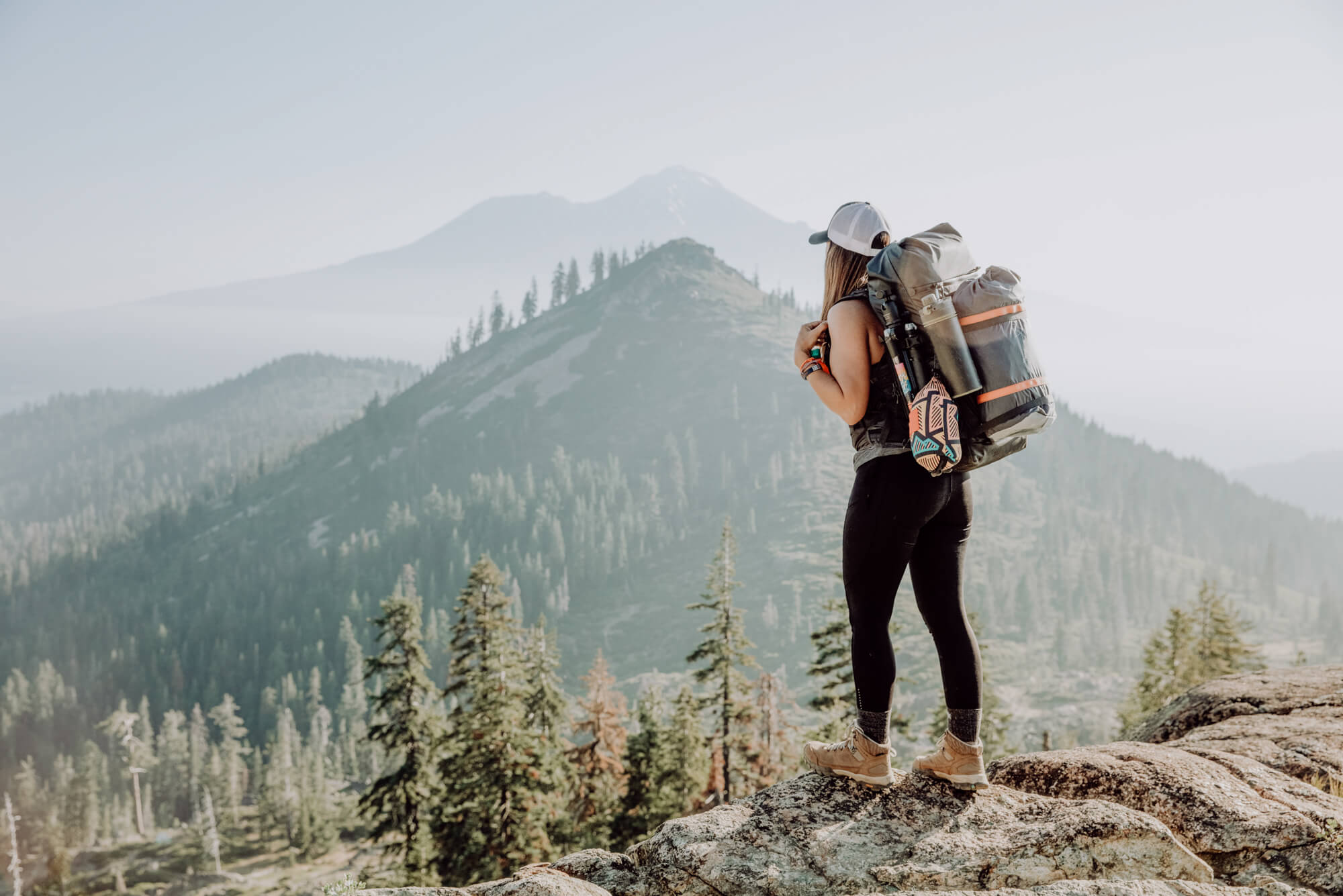 Eine Frau mit Wanderrucksack schaut in die Berge.