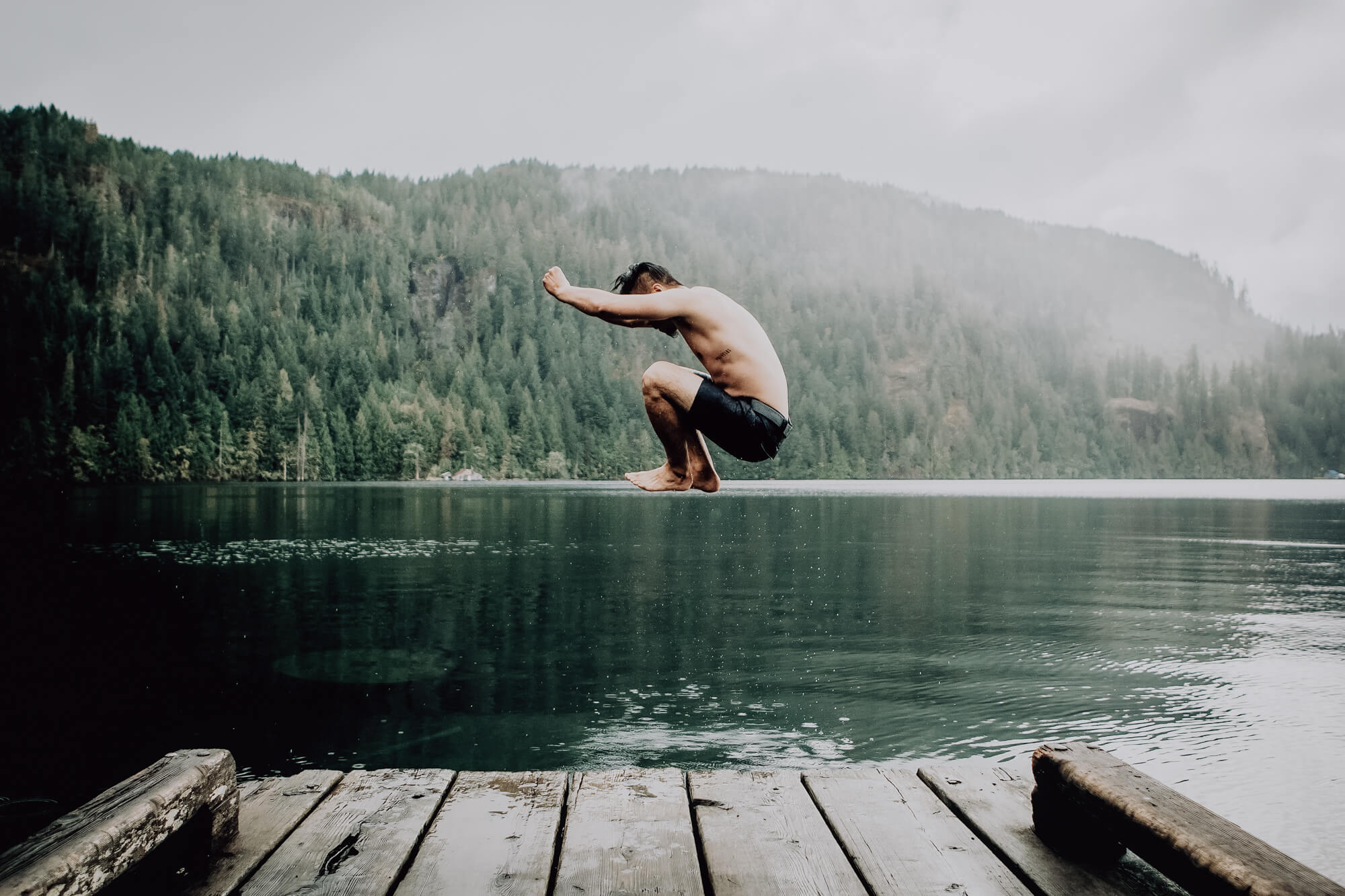 Ein junger Mann springt in einen Bergsee.